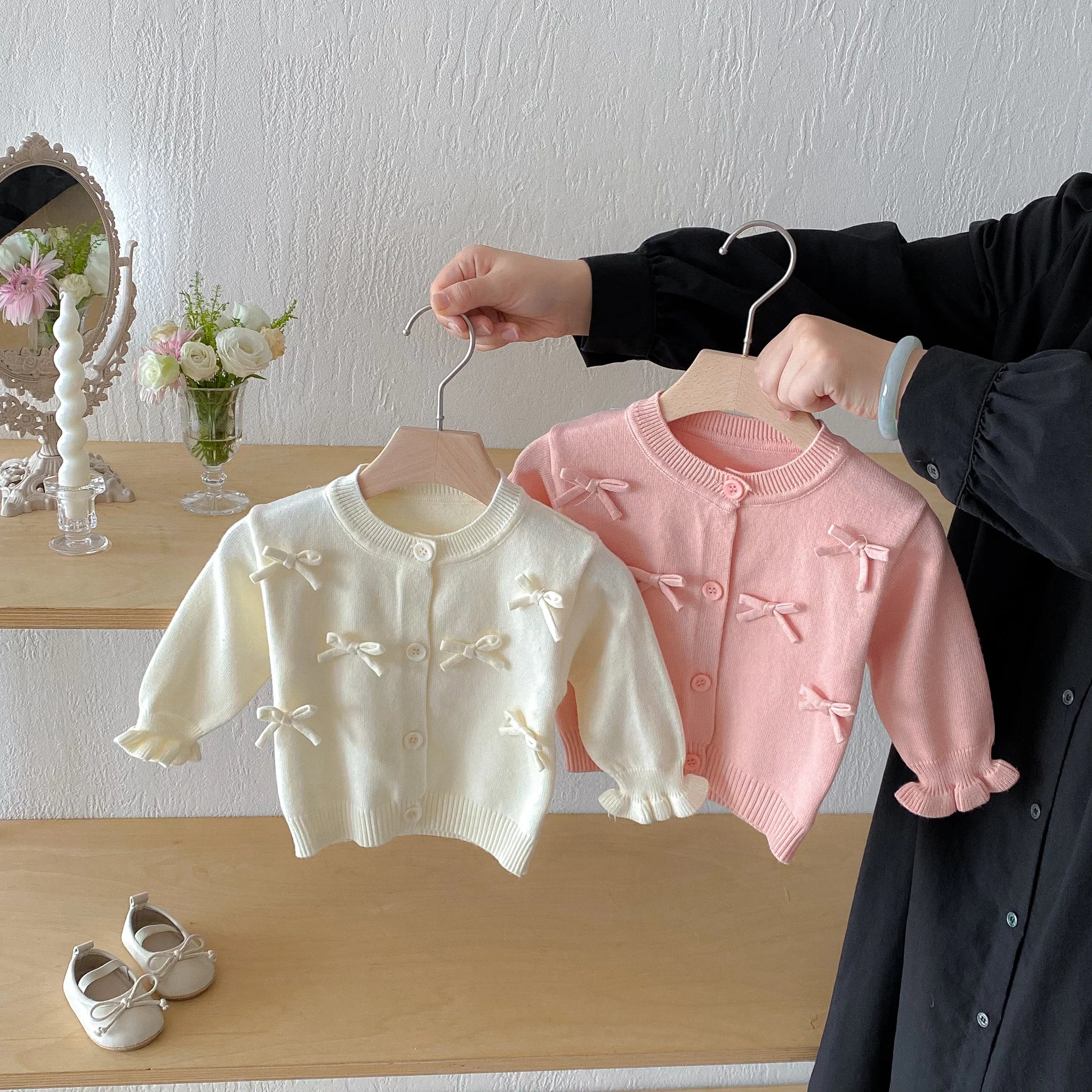 A cute long-sleeved cardigan with a bow for a baby girl in autumn