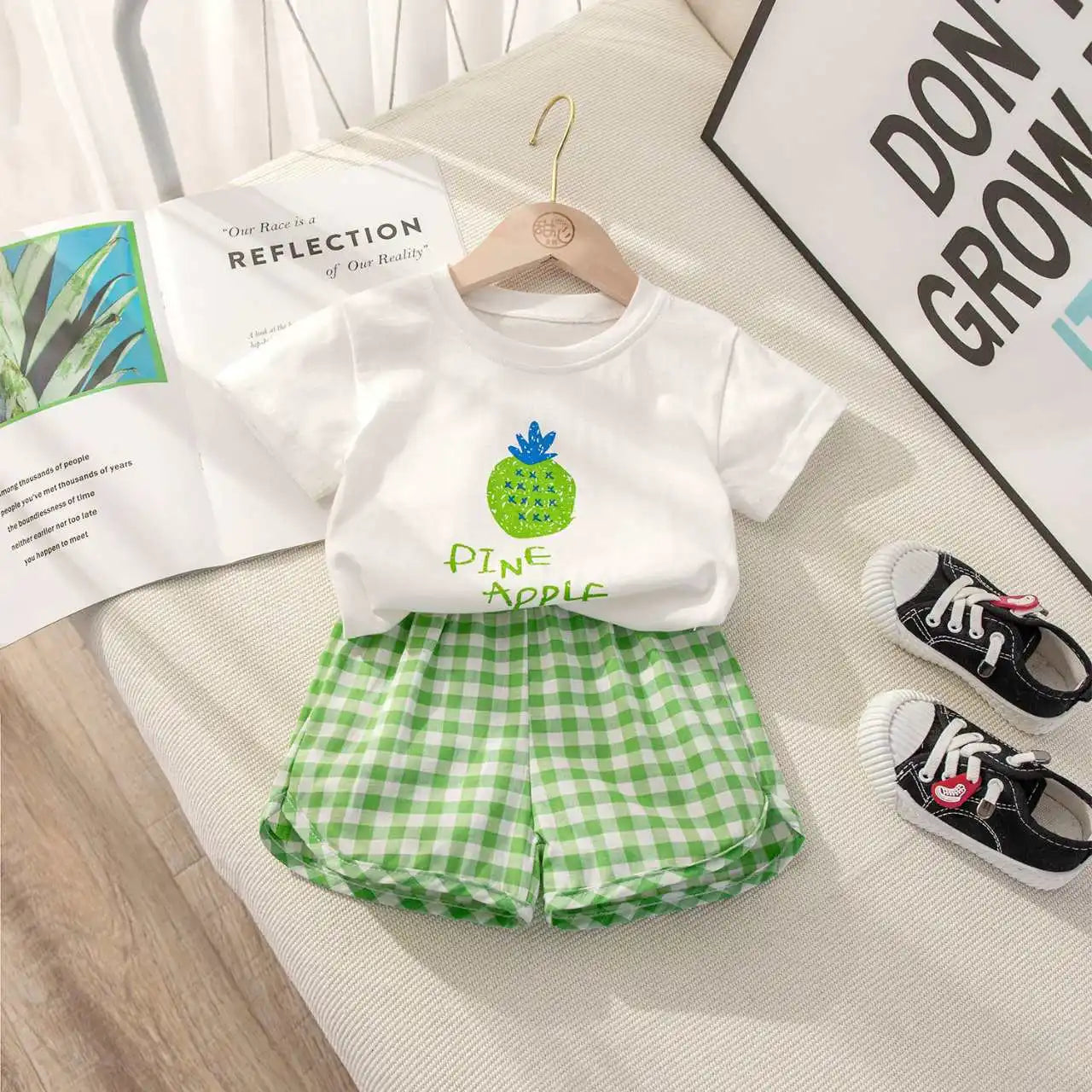 Children's summer casual set by I YAN featuring a short-sleeved round neck top with fruit and cartoon grape and lemon prints and plaid shorts.