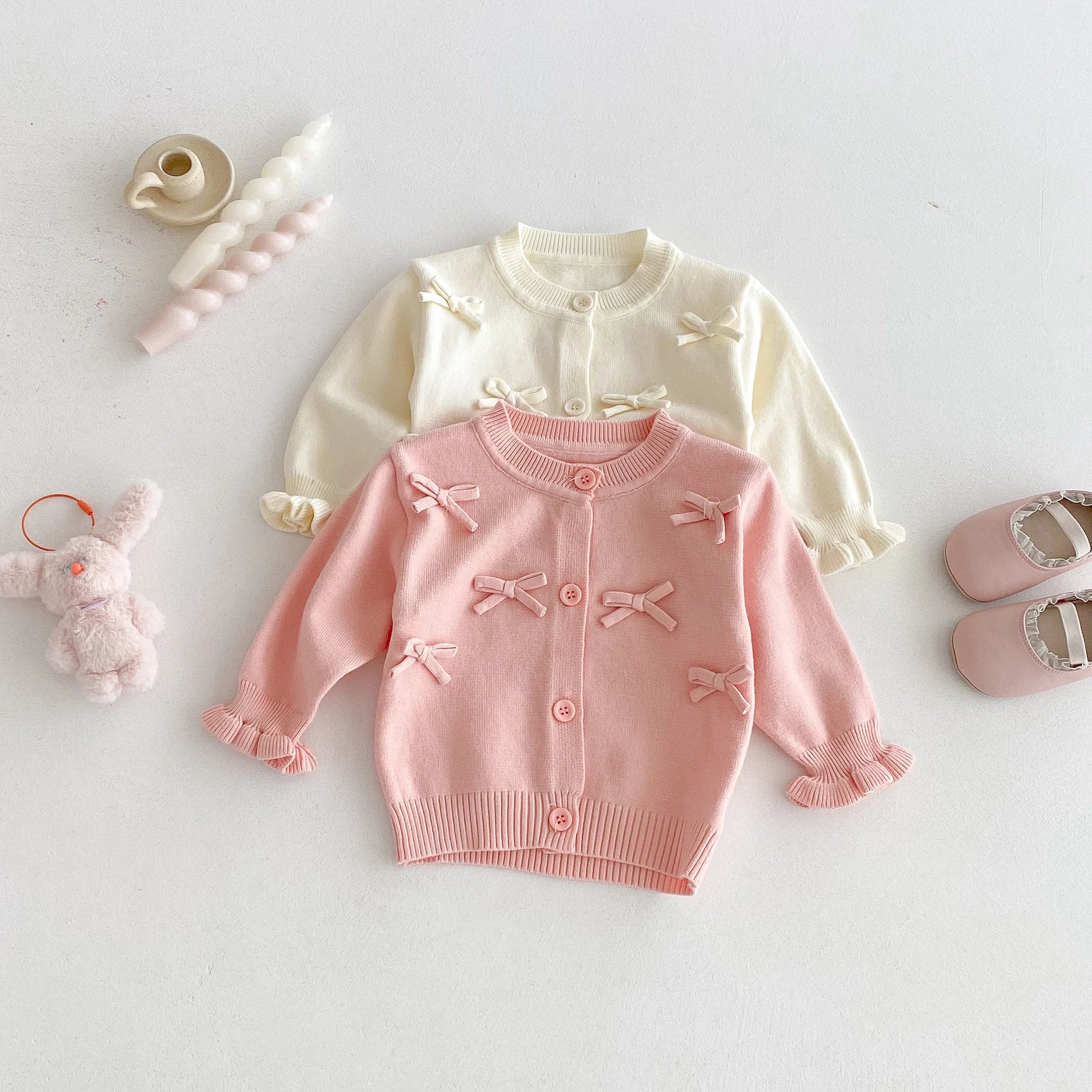 A cute long-sleeved cardigan with a bow for a baby girl in autumn