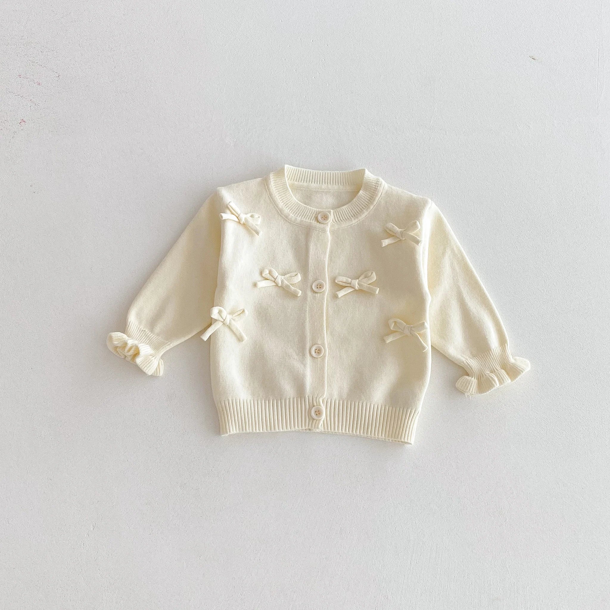 A cute long-sleeved cardigan with a bow for a baby girl in autumn