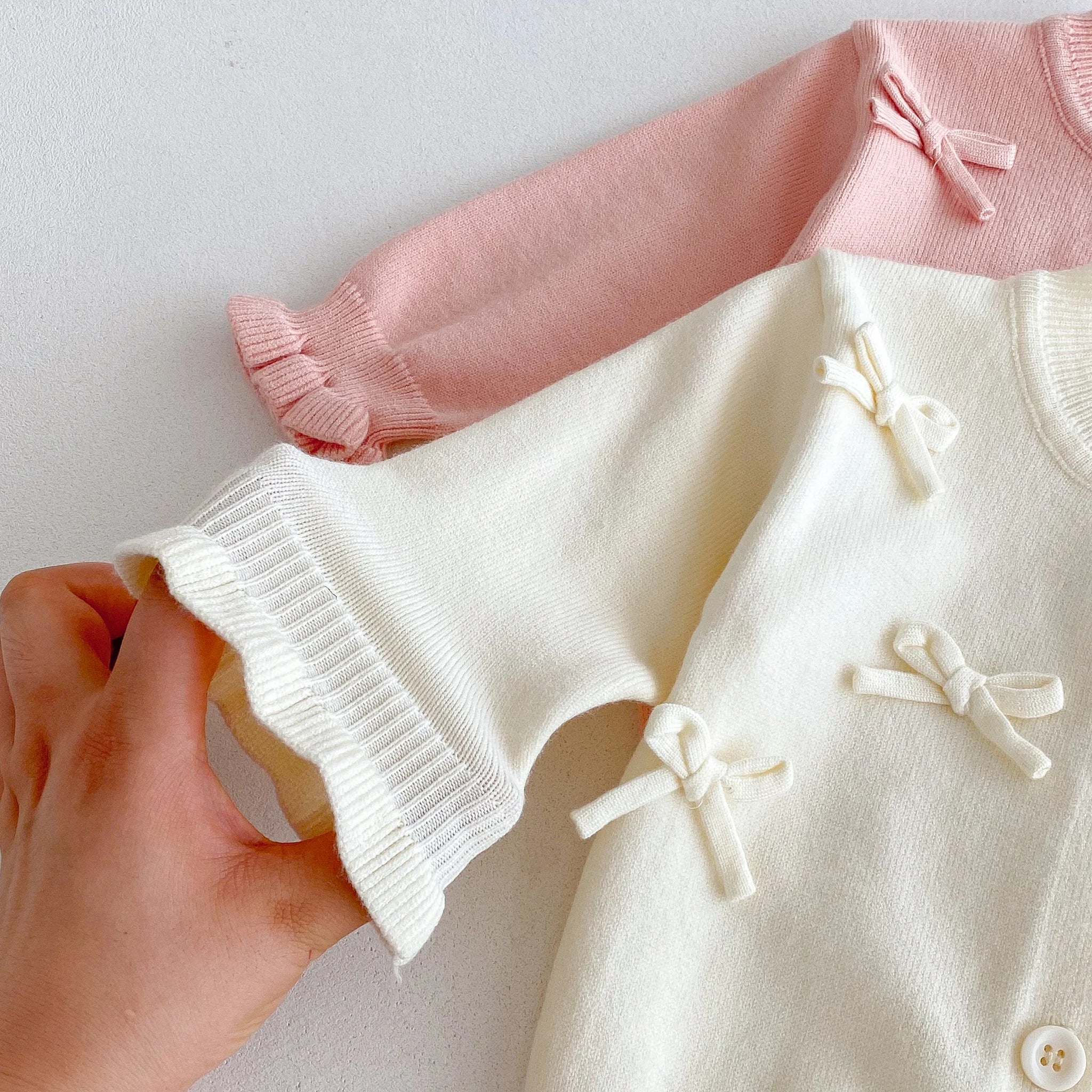 A cute long-sleeved cardigan with a bow for a baby girl in autumn